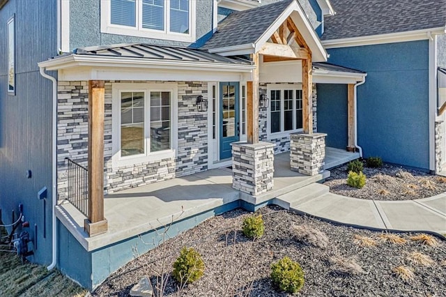 view of exterior entry featuring a shingled roof, covered porch, metal roof, stone siding, and a standing seam roof