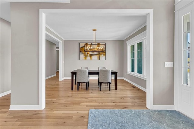 dining space featuring light wood-style floors, baseboards, a chandelier, and ornamental molding