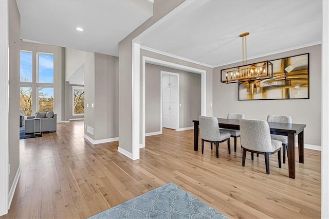 dining area with light wood finished floors, a notable chandelier, baseboards, and ornamental molding