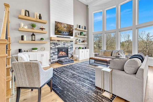 living room with light wood-type flooring, a high ceiling, and a fireplace