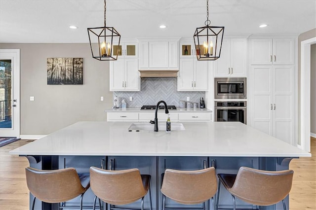 kitchen featuring white cabinets, light wood-type flooring, appliances with stainless steel finishes, and a sink