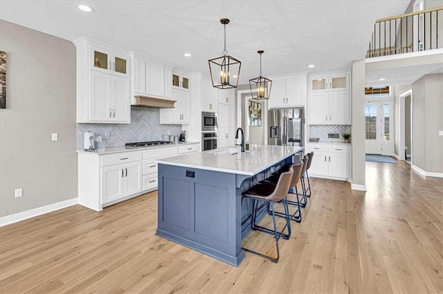 kitchen featuring baseboards, light countertops, appliances with stainless steel finishes, light wood-style floors, and white cabinets