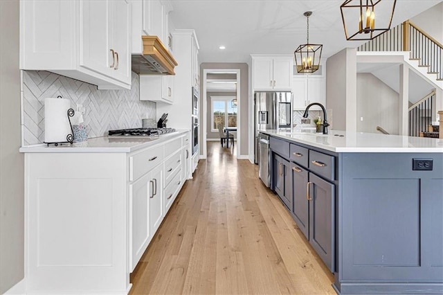 kitchen featuring a sink, appliances with stainless steel finishes, white cabinets, light countertops, and custom exhaust hood