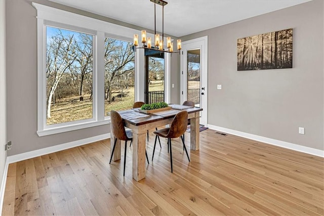 dining area with an inviting chandelier, light wood-style flooring, visible vents, and baseboards