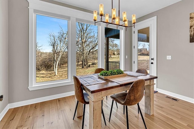 dining space featuring visible vents, baseboards, a notable chandelier, and light wood finished floors