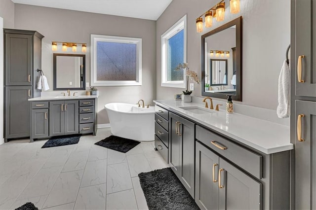 full bathroom with a sink, a freestanding tub, two vanities, and marble finish floor