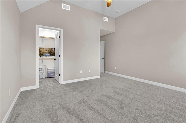 unfurnished bedroom with carpet, visible vents, baseboards, lofted ceiling, and a walk in closet