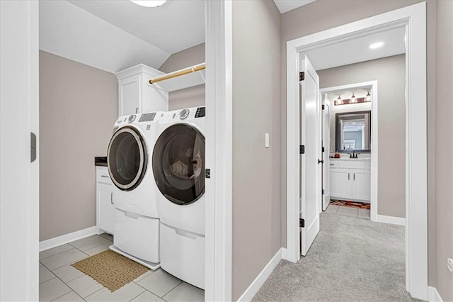 clothes washing area with light tile patterned floors, baseboards, cabinet space, and separate washer and dryer