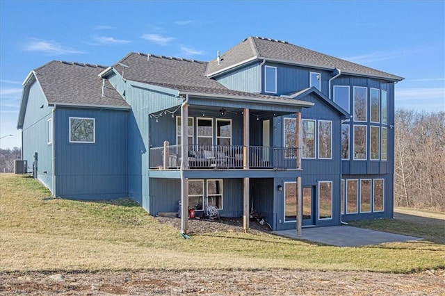 rear view of property featuring a patio, central AC unit, a lawn, and a shingled roof