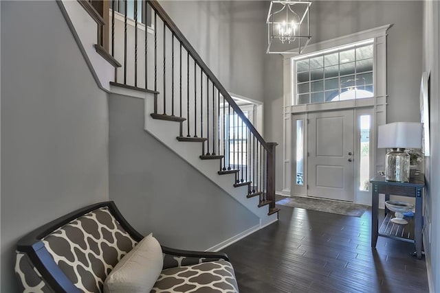 entryway featuring baseboards, dark wood finished floors, a high ceiling, stairs, and a chandelier