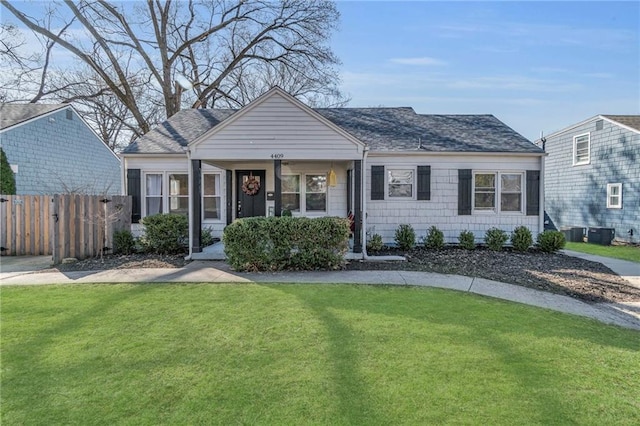 view of front of property with central air condition unit, roof with shingles, a front yard, and fence