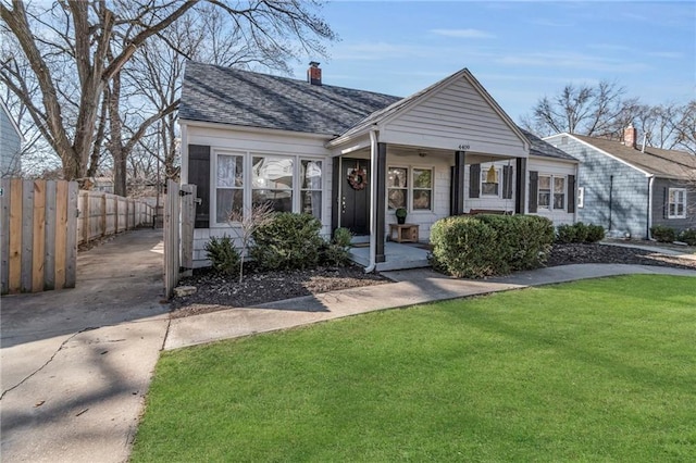 view of front of property featuring fence, roof with shingles, a chimney, a front lawn, and concrete driveway