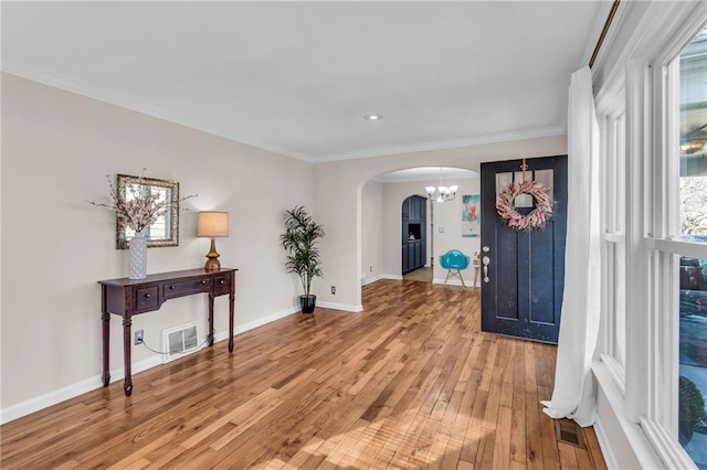 foyer featuring visible vents, baseboards, light wood-style flooring, arched walkways, and a notable chandelier