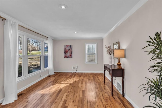 unfurnished room with a wealth of natural light, baseboards, light wood-style floors, and ornamental molding