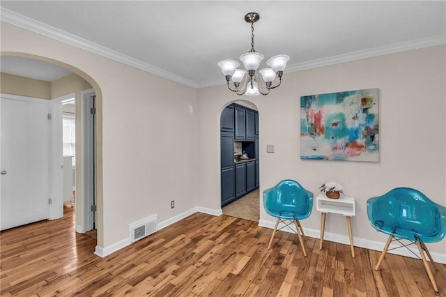 unfurnished room with visible vents, arched walkways, and light wood-style flooring