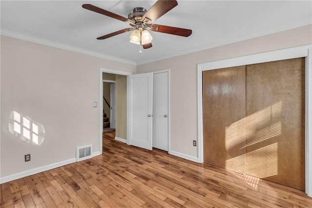 unfurnished bedroom with visible vents, crown molding, baseboards, and wood-type flooring