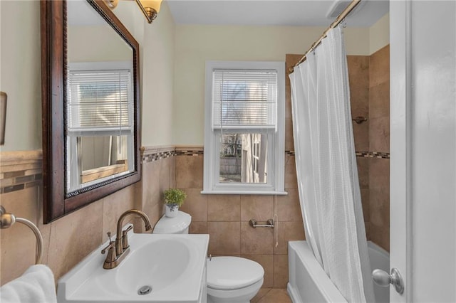 bathroom featuring tile walls, toilet, a wealth of natural light, and a sink