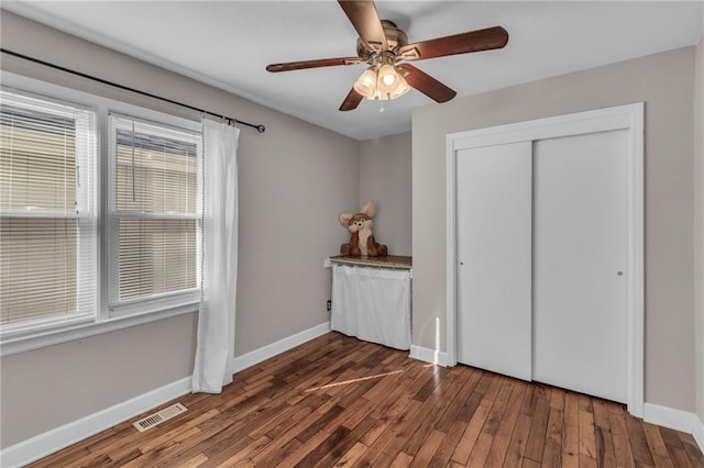 unfurnished bedroom with visible vents, ceiling fan, baseboards, a closet, and wood-type flooring