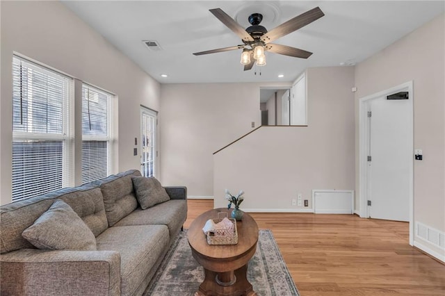 living area featuring visible vents, baseboards, light wood-style flooring, and a ceiling fan