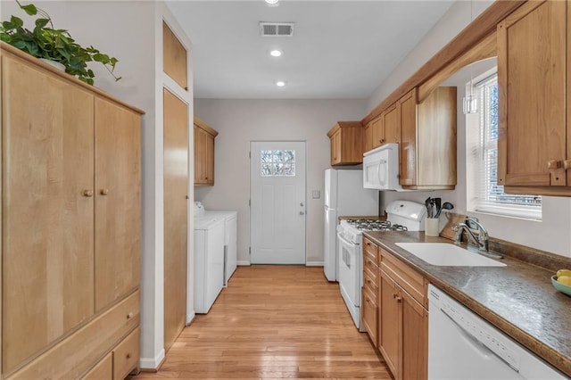 kitchen with white appliances, visible vents, light wood finished floors, washing machine and clothes dryer, and a sink