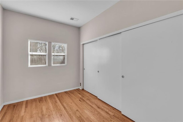 unfurnished bedroom featuring light wood finished floors, visible vents, baseboards, and a closet