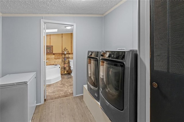 washroom featuring separate washer and dryer, a heating unit, ornamental molding, a textured ceiling, and light wood-type flooring