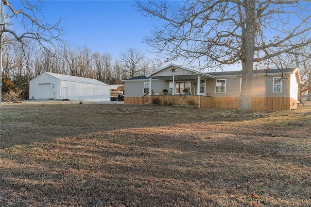 view of front of home with an outbuilding, a porch, a detached garage, and a front yard