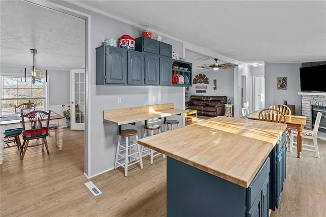 kitchen with a glass covered fireplace, light wood-style flooring, wood counters, and blue cabinets