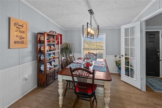 dining room with a notable chandelier, wainscoting, ornamental molding, and wood finished floors