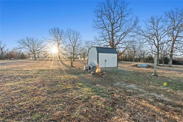 view of yard featuring a shed, an outdoor fire pit, and an outdoor structure