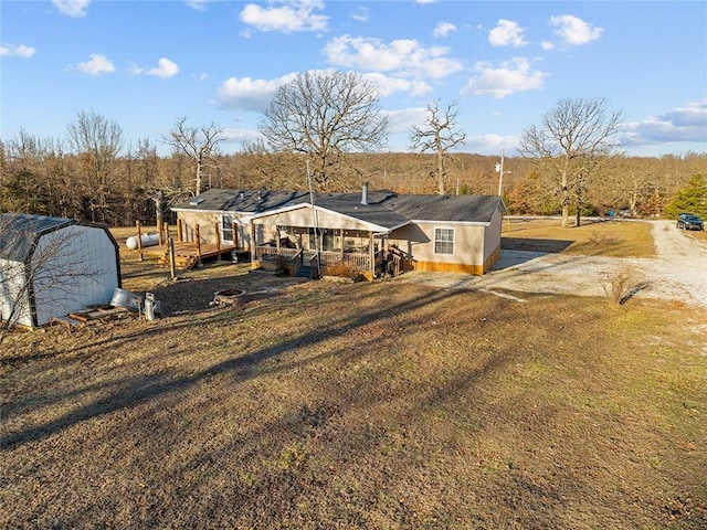 back of property featuring a wooden deck and dirt driveway