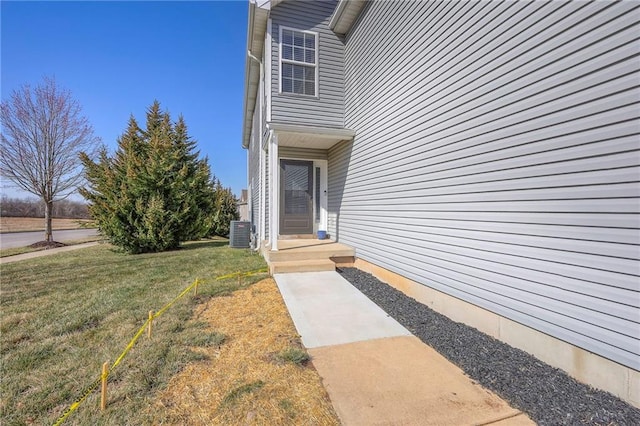 entrance to property featuring a lawn and central AC unit