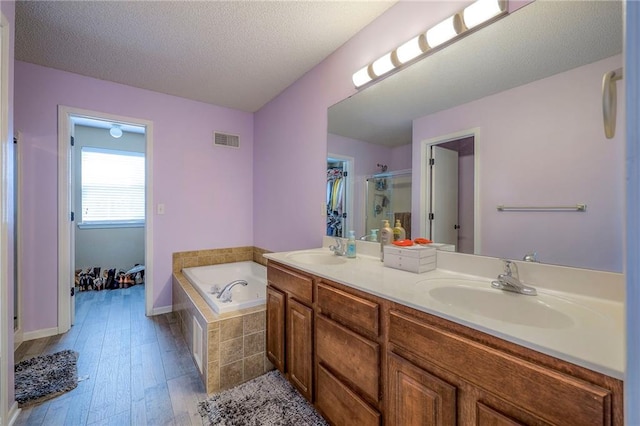 bathroom featuring visible vents, double vanity, a stall shower, a bath, and a sink