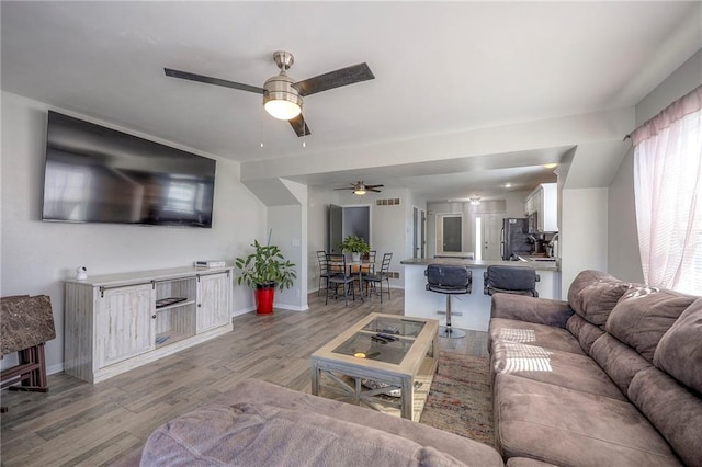 living area with light wood-style flooring, baseboards, and ceiling fan