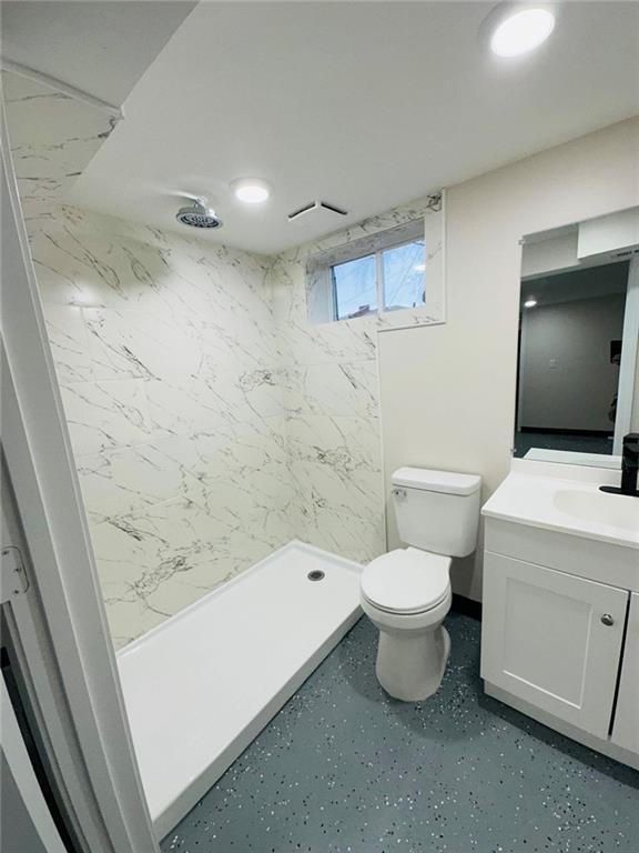 bathroom with toilet, a stall shower, and vanity