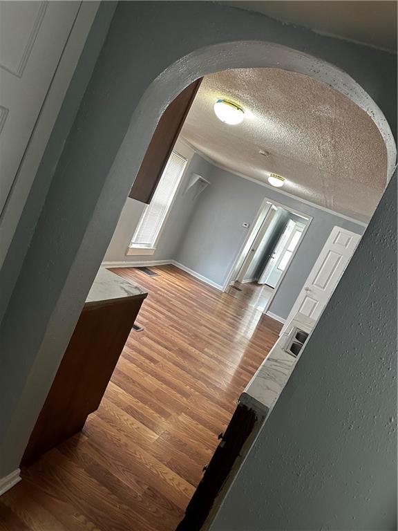 480 Wallace Ave, Kansas City, MO 64125 - hallway featuring lofted ceiling, a textured ceiling, wood finished floors, arched walkways, and baseboards