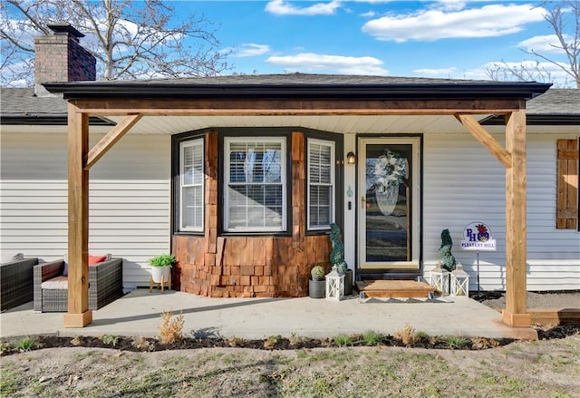 doorway to property with covered porch and a chimney