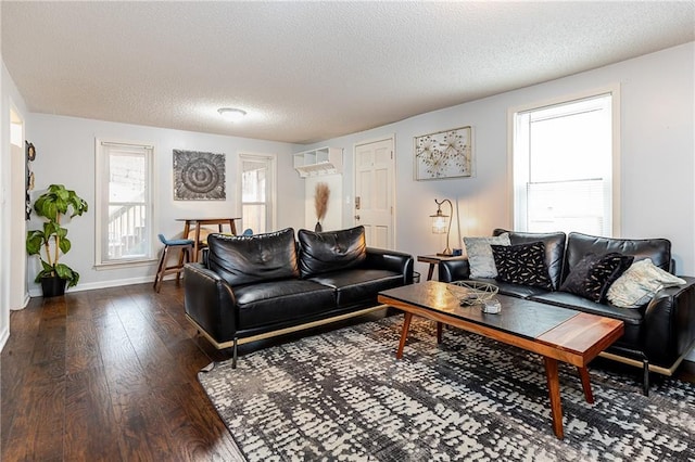 living area featuring a textured ceiling, baseboards, and wood finished floors