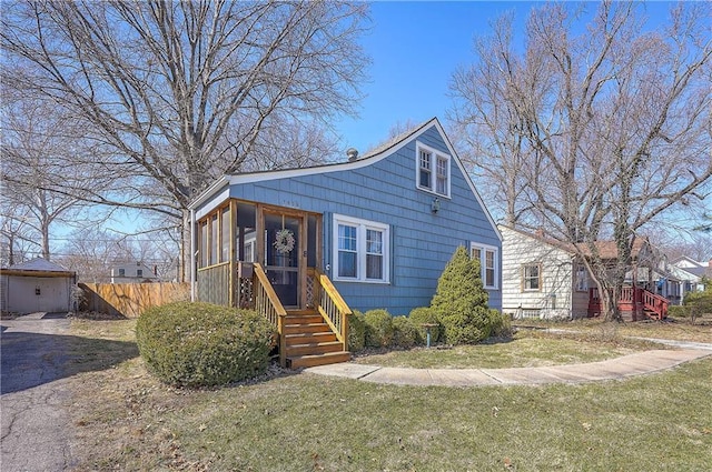 view of front of property with a front yard, fence, and a sunroom