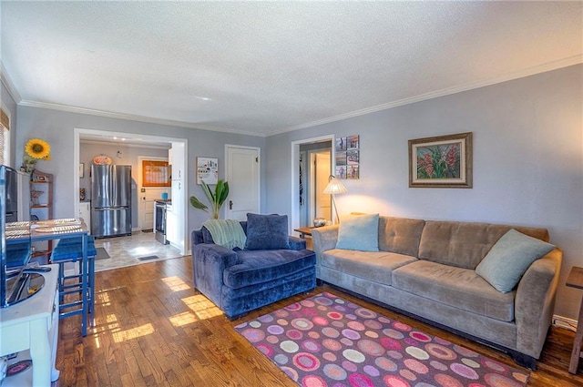 living room featuring ornamental molding, visible vents, wood-type flooring, and a textured ceiling