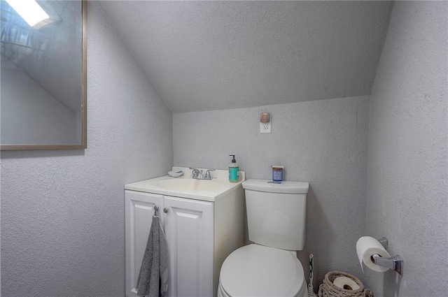 bathroom with lofted ceiling, toilet, and a textured wall