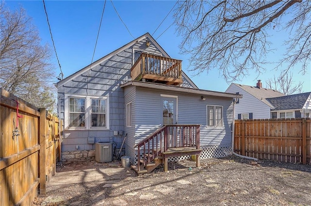 back of house with central air condition unit, a balcony, and a fenced backyard