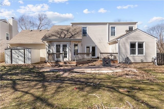 back of house featuring an outbuilding, fence, french doors, a storage shed, and a wooden deck