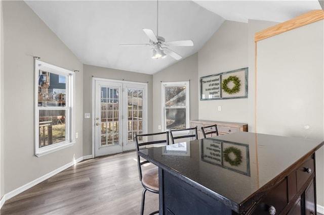 dining area with a wealth of natural light, vaulted ceiling, ceiling fan, and wood finished floors