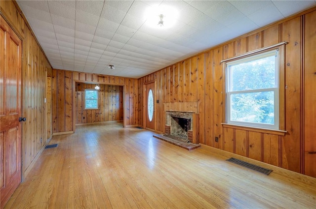 5200 NW Valley View Rd, Blue Springs, MO 64015 - unfurnished living room with a stone fireplace, light wood-style floors, baseboards, and wood walls