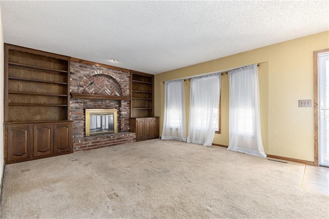 unfurnished living room featuring built in shelves, a textured ceiling, and a fireplace