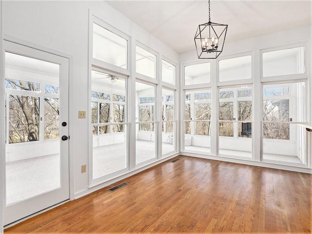 unfurnished sunroom featuring visible vents and ceiling fan with notable chandelier