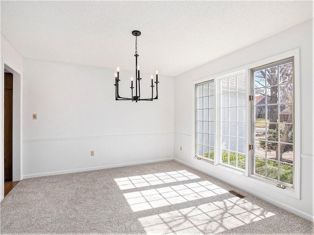 unfurnished dining area with visible vents, a textured ceiling, an inviting chandelier, and carpet floors