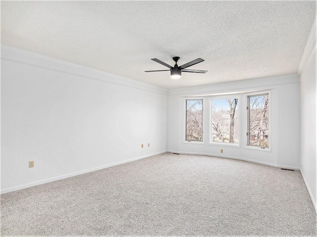 carpeted empty room with a ceiling fan, visible vents, baseboards, a textured ceiling, and crown molding