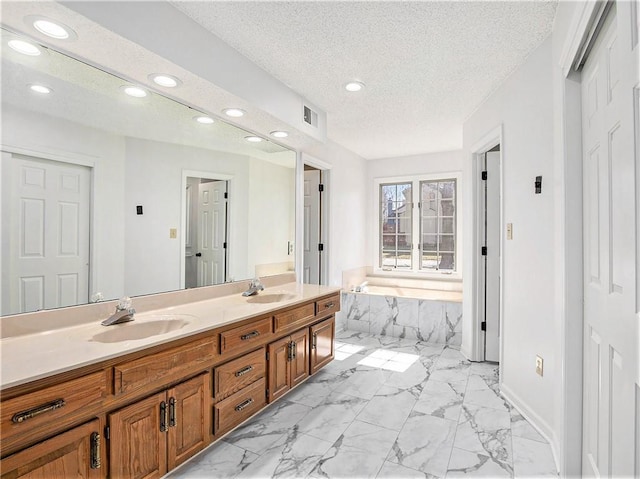 full bathroom with visible vents, a sink, a textured ceiling, a garden tub, and marble finish floor